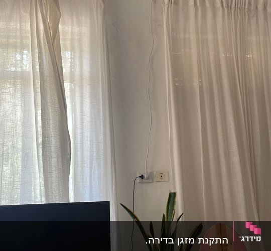 מזגן מותקן על קיר עם כבל חשמל מחובר